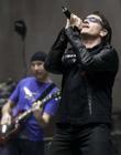 With band member Edge in the background, Bono of the group U2 performs at the Baltimore Arena in Baltimore, Maryland October 19, 2001. Bono and Edge will be joining many other performers at the 